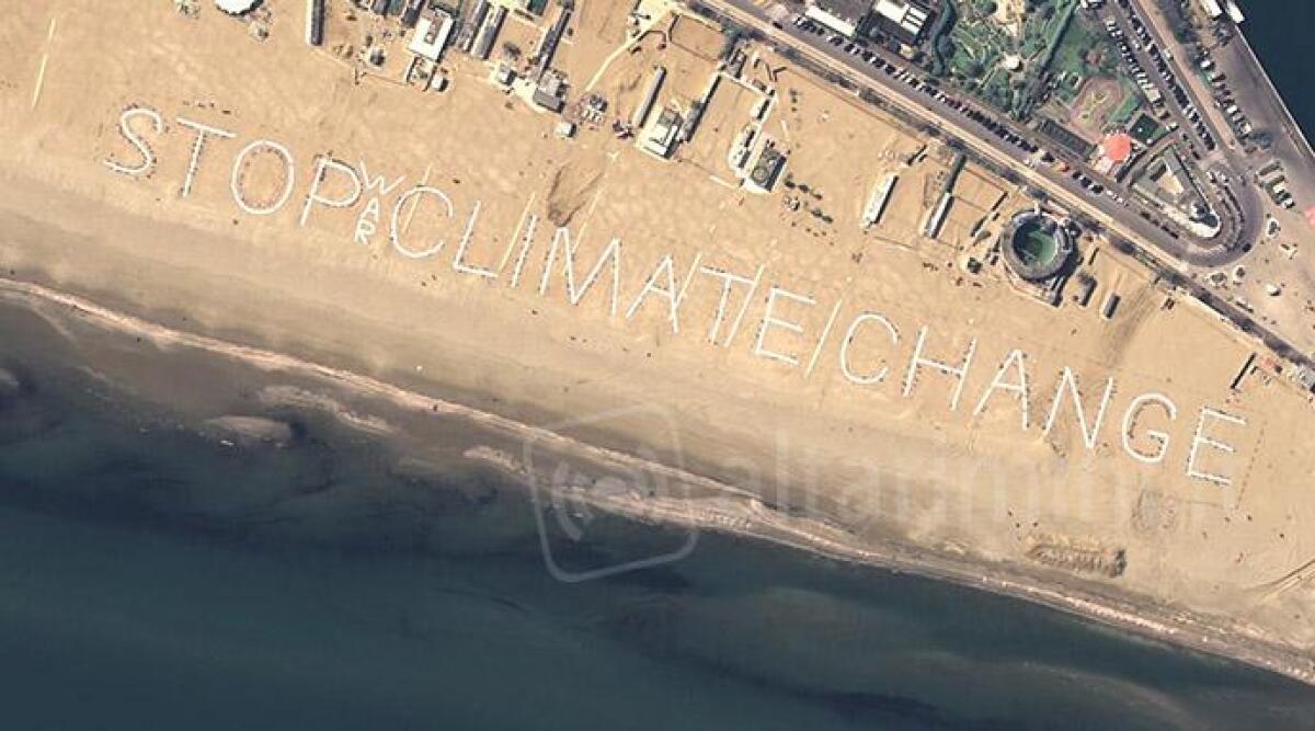 Una scritta umana sulla spiaggia per dire stop guerra e cambiamenti climatici: la foto dal satellite - 