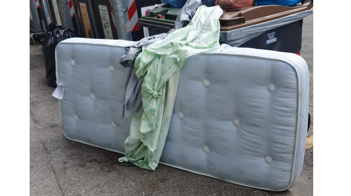 Degrado in pieno centro: tra i sacchi di immondizia fuori dal cassonetto anche un materasso - Via Clementini, Rimini. Foto scattata da un lettore
