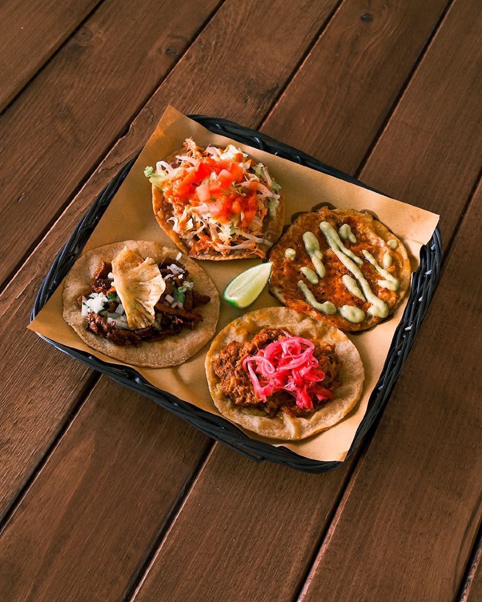In basso a sinistra taco al pastor con ananas tostato, e a destra in basso taco di cochinita pibil.In alto a sinistra sempre tostada di tinga di pollo e in alto a destra quesadilla con chorizo e salsa verde